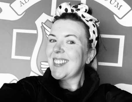 black and white picture of a woman smiling in front of a school crest
