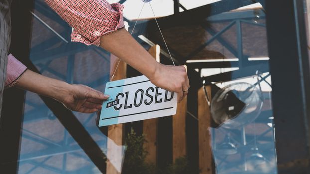 hands putting up a closed sign on a restaurant