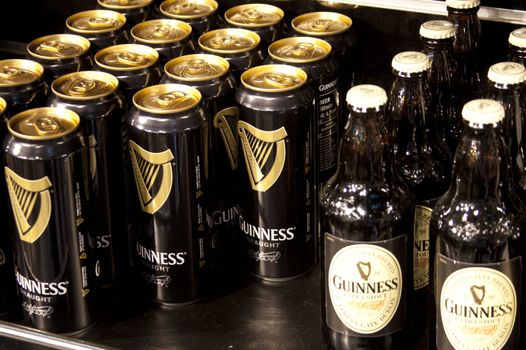 close up of multiple cans and bottles of guinness, positioned facing forward on a shelf