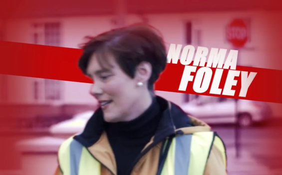 side profile shot of Fianna Fáil minister Norma Foley in a high vis vest with a red background and white block letters which read "Norma Foley"