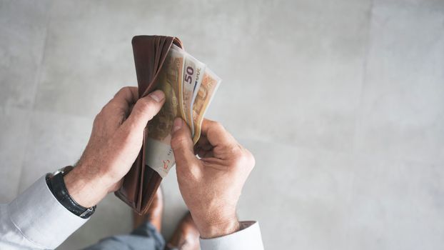 hands holding open a wallet with €50 notes inside