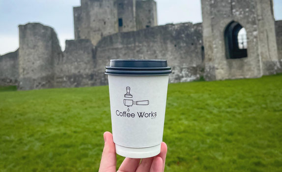 Coffee Works cup being held up outside Trim Castle