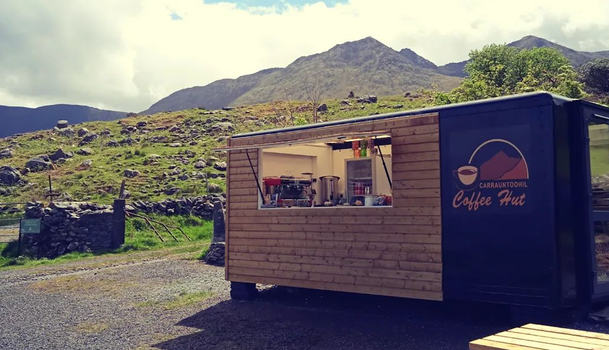 wooden coffee hut with a mountain and blue sky behind it