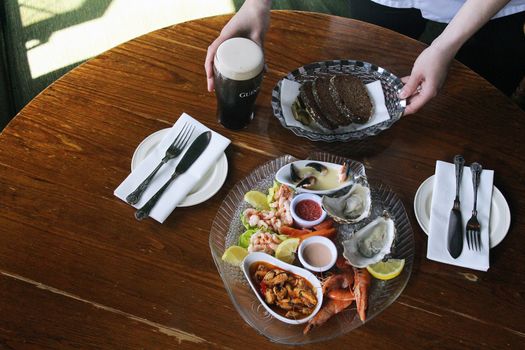 a table with two sets of cutlery, a pint and a seafood platter