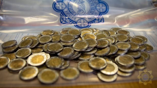 a pile of fake €2 coins on top of a gardai evidence plastic bag