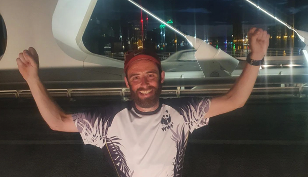 runner smiling and holding up his hands in victory on Millennium Bridge in Dublin