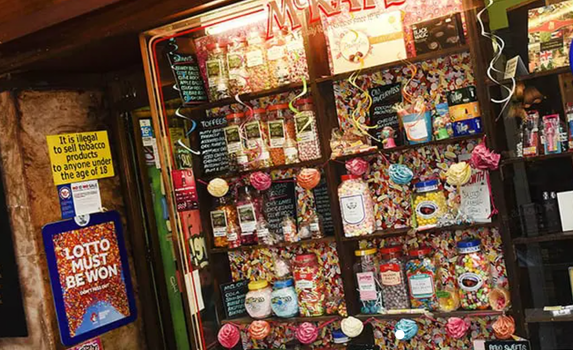 old fashioned sweet shop with several jars of sweets lined up on shelves behind the counter