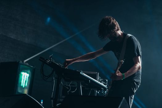 silhouette of a musician on stage playing guitar and adjusting keyboard settings