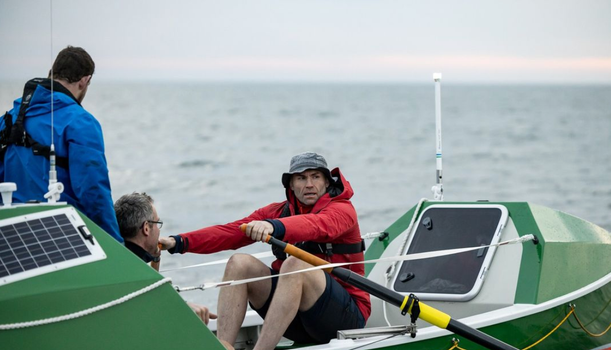 man in a green row boat with red jacfket and bucket hat