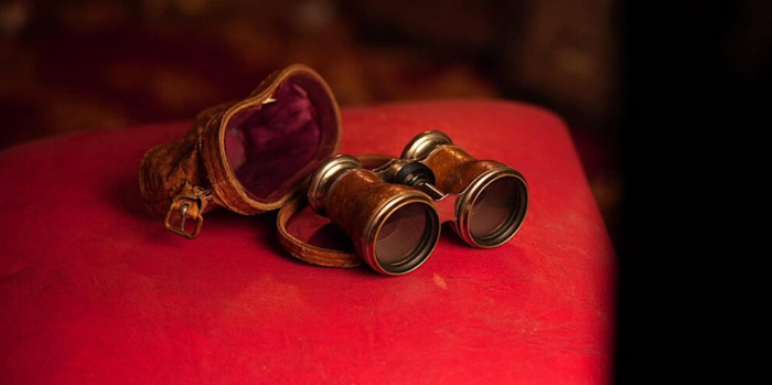 old fashioned cinema viewing binoculars on a red velvet seat