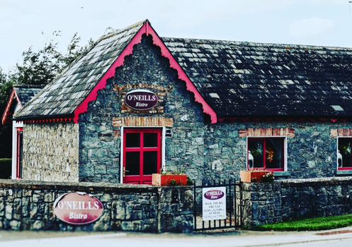 traditional stone cottage with red window frames and decals in Tipperary, bistro inside