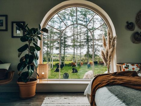 farmhouse-style bedroom with large window, cows on the grass outside