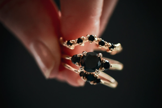close up of a hand holding three gold rings with black diamonds
