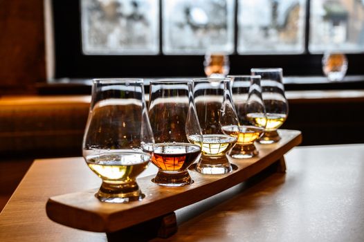 selection of whiskeys in glasses, on top of a wooden board
