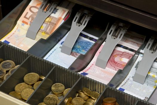 an open cash register with euro notes and coins inside