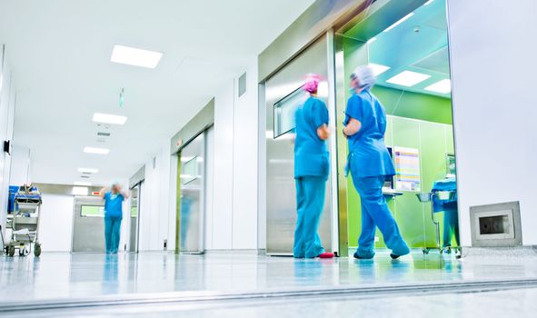 blurred image of a hospital corridor with two nurses in scrubs