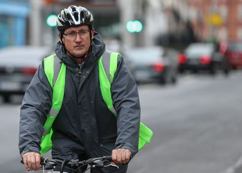 eamon ryan riding a bike, wearing a hi vis and helmet