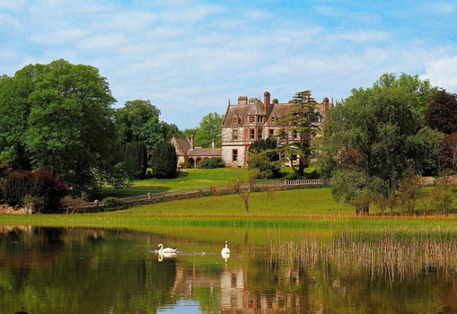 exterior of castle leslie, a hotel set on a large estate with a lake with swans in front