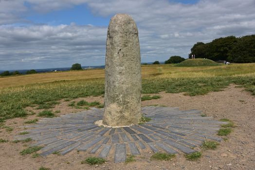 the Hill of Tara standing stone, with fields and blue sky in the background
