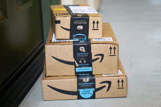a pile of amazon packages waiting outside a front door