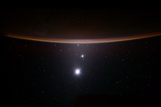 jupiter, venus and a crescent moon as seen from the distance in space