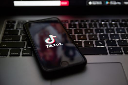 a smart phone sitting on top of a laptop keyboard with the tiktok app open