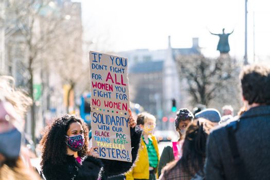 Woman at a protest holding up a sign that reads "If you don't fight for all women you fight for no women"