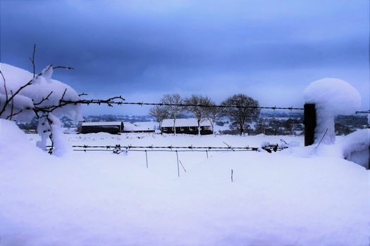 heavy snow on a wire fence surrounding a field